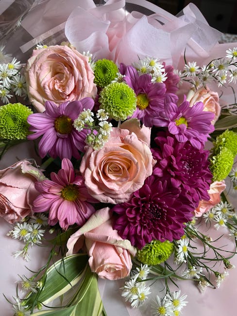 A close-up view of a fresh floral bouquet arranged by Worcester Park Florist, featuring large pale pink roses with soft, velvety petals, vibrant purple daisies with yellow centers, bright green chrysa