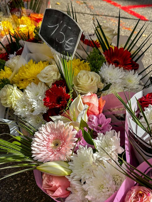 A vibrant floral arrangement featuring a variety of fresh flowers, including large pink gerbera daisies, white roses, red gerbera daisies, and white chrysanthemums, all artistically arranged with gree